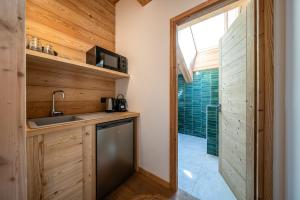 a kitchen with wooden walls and a sink and a shower at Chalet Ski Académie - Serre Chevalier in Saint-Chaffrey