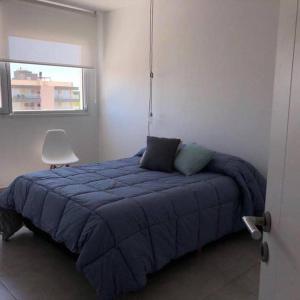 ein Schlafzimmer mit einem Bett mit einer blauen Decke und einem Stuhl in der Unterkunft Carpe Diem Monte Hermoso in Monte Hermoso + 4 Fotos