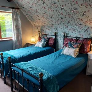 2 Betten in einem Schlafzimmer mit Blumentapete in der Unterkunft The Captain's Cottage at Climping in Climping