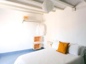 a white bedroom with a white bed with yellow pillows at Vila Closa Juncosa in Juncosa