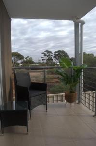 a balcony with a chair and a table and a plant at Modern Apartment in Roxby Downs in Roxby Downs