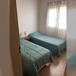 twee bedden in een kleine kamer met een raam bij Zorzal Tempo in Esquel