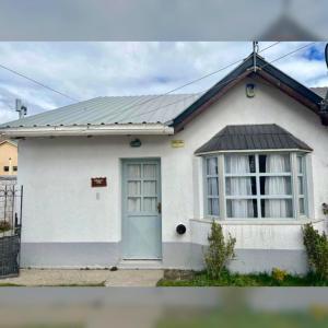 een klein wit huis met een blauwe deur bij Zorzal Tempo in Esquel