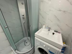 a bathroom with a shower and a sink and a washing machine at 1-комнатная квартира с дизайнерским ремонтов в районе Вокзала in Petropavlovsk
