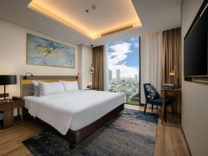 ein Hotelzimmer mit einem Bett und einem großen Fenster in der Unterkunft Mövenpick Living West Hanoi in Hanoi