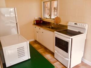 een keuken met een wit fornuis en een wastafel bij Mollies Place - Waihi Beach Holiday Unit in Waihi Beach