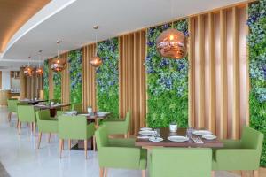 ein Esszimmer mit Tischen, Stühlen und Pflanzen in der Unterkunft Hilton Dubai Creek Hotel & Residences in Dubai