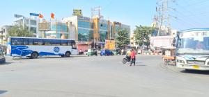 a city street with buses and a person on a bike at Hotel Vivan in Vadodara
