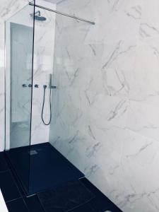 een badkamer met een douche en witte marmeren muren bij Beautiful ocean view home in Paço de Arcos