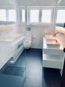 a white bathroom with two sinks and a toilet at Beautiful ocean view home in Paço de Arcos