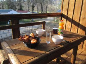 una mesa de madera con una cesta de comida en el porche en Camping la Borie Basse en Condat