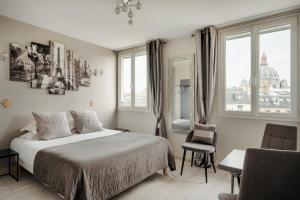 a bedroom with a bed and two windows at Hôtel d'Argenson in Paris