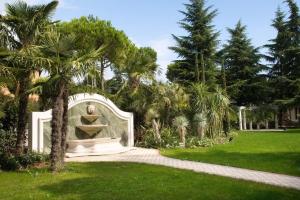 una fuente en medio de un parque con palmeras en Monastero Resort & Spa - Garda Lake Collection, en Soiano del Lago