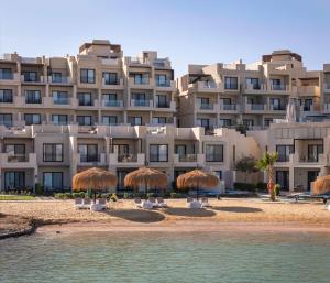 un gran edificio con sombrillas de paja en la playa en Creek Hotel and Residences El Gouna en Hurghada