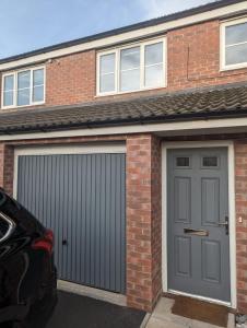 a garage with a gray door and a brick building at Freshen-up stays Doncaster in Bentley