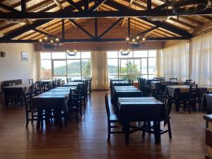 a dining room with tables and chairs and windows at HPP Hotel in San Carlos de Bariloche