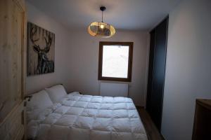 a bedroom with a white bed and a window at Le Balcon du Snow Roc in Saint-Jean-d'Aulps