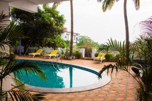 a swimming pool in a yard with palm trees at TTH in Goa Velha