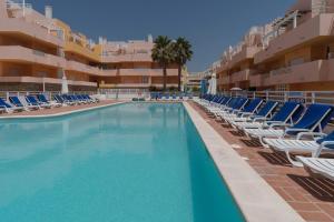 una piscina con tumbonas y un hotel en NEW !! One Bedroom Cabanas Tavira - Banda Musical Blue, en Tavira