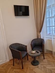 シビウにあるStudio Piața Mareの椅子2脚、テーブル、テレビが備わる客室です。