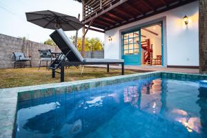 a pool with a hammock and an umbrella next to a house at Villa dos Poetas in Barra Grande
