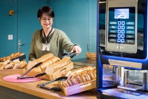 a woman standing behind a counter with some hot dogs at Fasthotel Limoges in Limoges