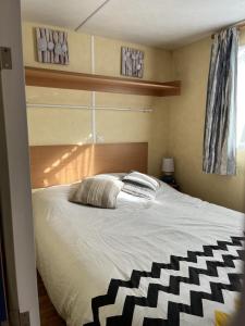 Schlafzimmer mit einem Bett mit einer schwarzen und weißen Bettdecke in der Unterkunft mobil-home 4/6 pers in Les Moutiers-les-Mauxfaits