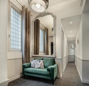 a living room with a green couch and a mirror at Hôtel d'Argenson in Paris