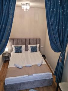 a bedroom with a large bed with blue curtains at Studio Piața Mare in Sibiu