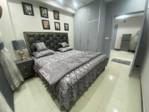 a bedroom with a large bed with a gray comforter at The Bahria Town Hotel & Suites in Lahore