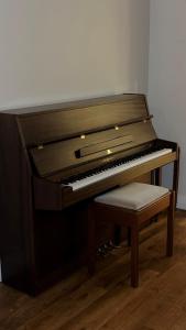 un piano brun avec un tabouret à côté dans l'établissement Bayview Cottage, à Lamlash