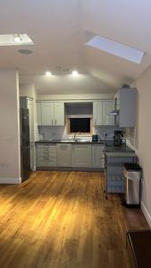 cocina con armarios blancos y suelo de madera dura en Bayview Cottage en Lamlash