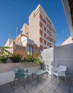 eine Terrasse mit 2 Stühlen und einer Bank und einem Gebäude in der Unterkunft Nature by Raidom in Alicante