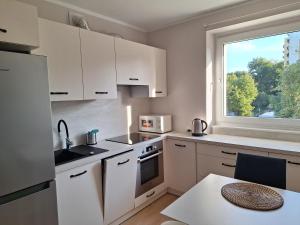 a kitchen with white cabinets and a window and a table at Apartament Kamienny Potok Sopot in Sopot
