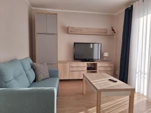 a living room with a blue couch and a tv at Apartament Kamienny Potok Sopot in Sopot