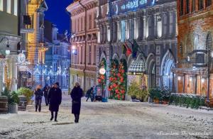 a group of people walking down a street with a christmas tree at St Palace Hotel in Vilnius