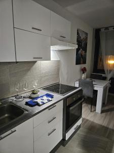 a kitchen with white cabinets and a sink and a stove at Apartman Luxe Victoria in Zagreb