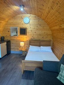 a bedroom with a bed and a clock on the wall at Original Glamping Pod with Hot Tub in Frodsham
