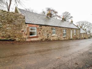 una vecchia casa in pietra sul ciglio di una strada di 8 Barney Mains Cottage a Haddington