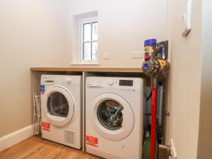 uma lavandaria com máquina de lavar e secar roupa em 8 Barney Mains Cottage em Haddington