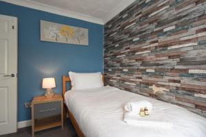 a bedroom with a bed and a brick wall at Spacious 4-Bed Family House in Portsmouth