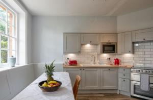 East Wing Apartment في ويموندهام: مطبخ مع طاولة عليها صحن من الفواكه