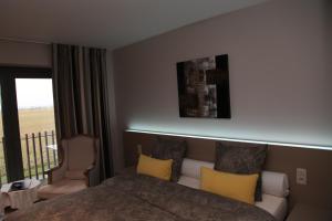 een slaapkamer met een bed met gele kussens en een balkon bij Hotel Callecanes in Poperinge