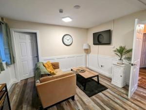 uma sala de estar com um sofá e um relógio na parede em The Cwtch Flat at The Lodge by Cefn Tilla em Usk