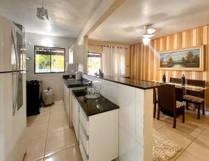 a large kitchen with a counter and a dining room at Chácara com Wi-Fi em São Pedro da Aldeia - RJ in São Pedro da Aldeia