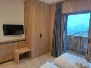 a bedroom with a large window and a tv at aMa Dolomiti Resort in Vigo di Cadore