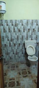 baño con aseo y pared de azulejos en Jagan Hotel And Restaurant en Bhara