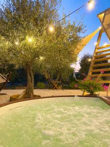 vasca idromassaggio in un cortile con un albero di A-luxury Glamping by La Mignola a Fasano