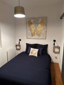 Un dormitorio con una cama azul con una pintura de mariposa en la pared en F2 à 500 m centre ville et gare - 1er étage en Soissons