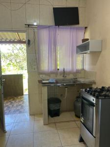 uma pequena cozinha com um lavatório e um fogão em Casa 2 na Praia Grande